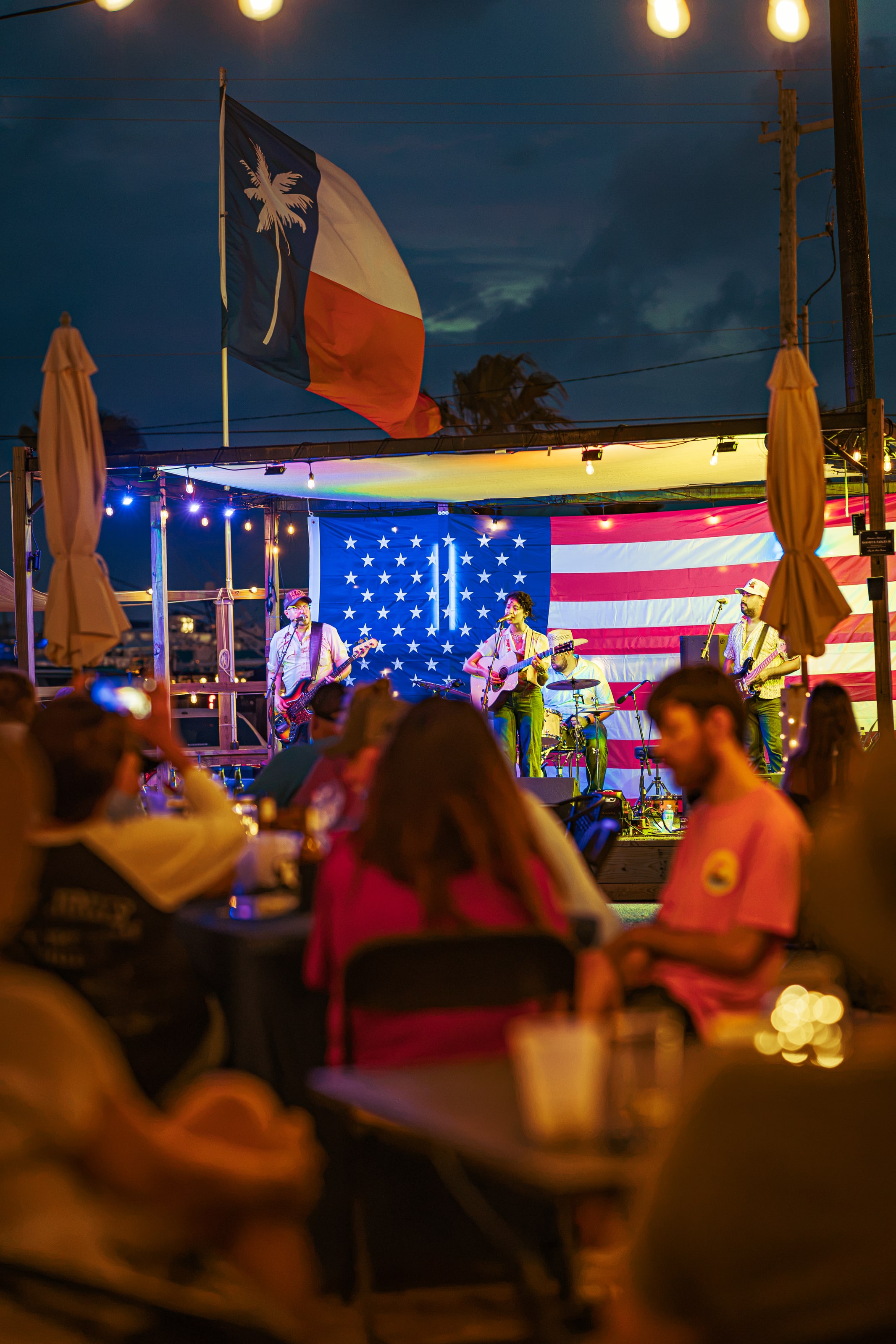 Palm Social Club patio, stage, and guests during an evening live-music event